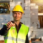 Construction worker holds out key to the house. Turnkey construction, relocation